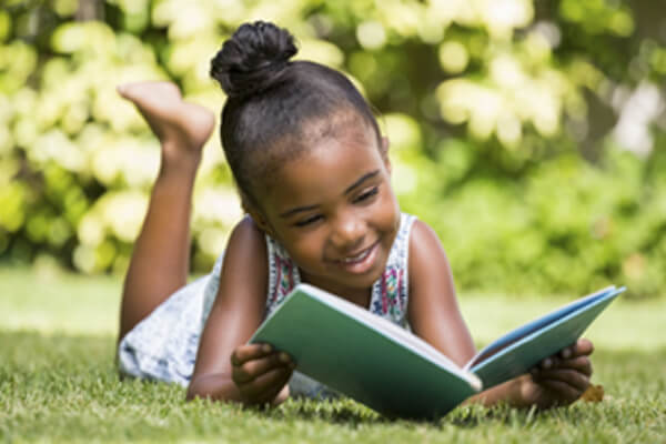 Primary Health Pediatrics Summer Reading Tips, Young girl reading outside, 