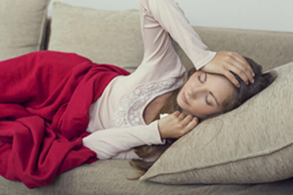 woman with flu symptoms laying on couch