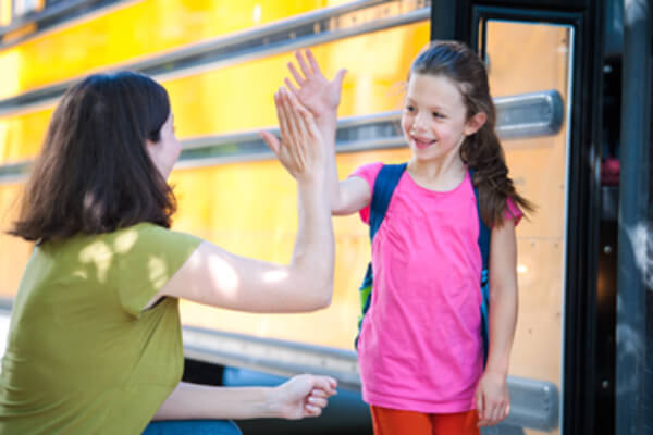 Mother taking daughter to school, getting on school bus