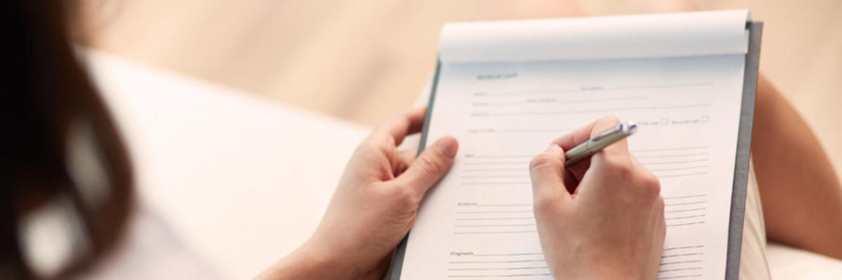 Woman filling out a form, or forms, on a clipboard