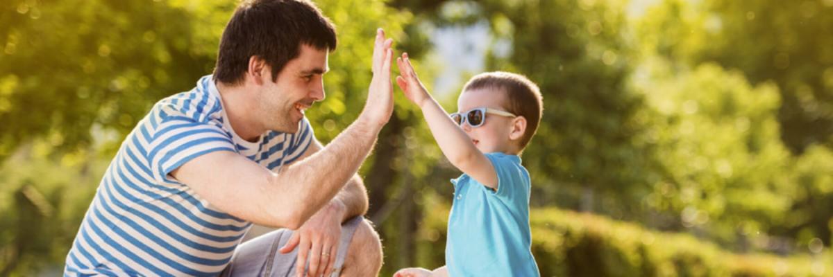 Dad and young son high-fiving outdoors, Parents and Caregivers