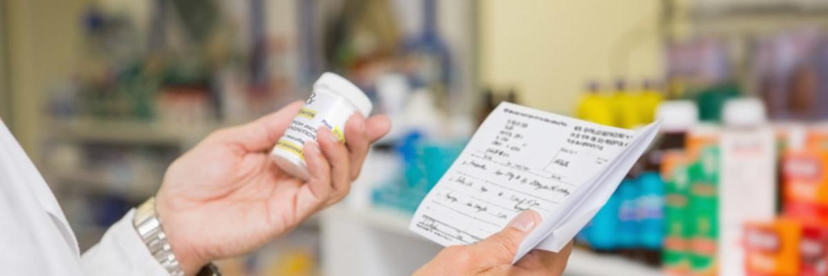 Pharmacist filling prescription, holding prescription paper