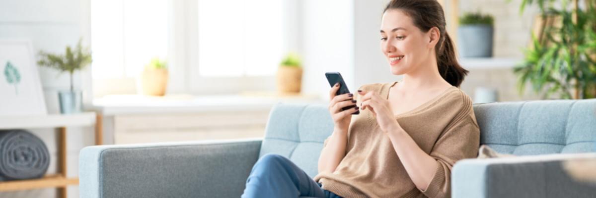 Young woman sitting on couch using cell phone, Telehealth Services