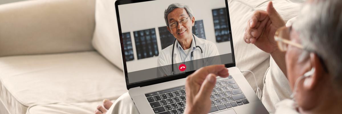 Elderly man using telehealth services on his laptop to talk to a doctor